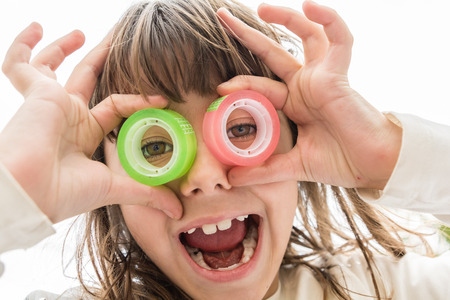 Beautiful little girl is looking through the circles of a  tapeの写真素材