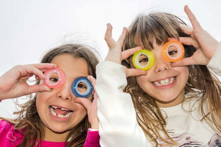 Two little girl are looking through the circles of a  tapeの写真素材