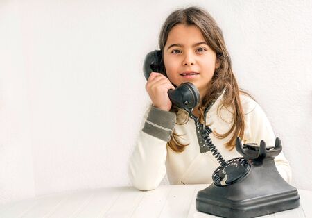 Seven year old girl with old vintage phone before white backgroundの写真素材