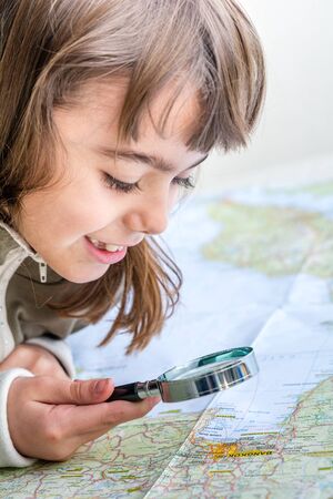 Concentrated seven year old girl examining the map with a loupe