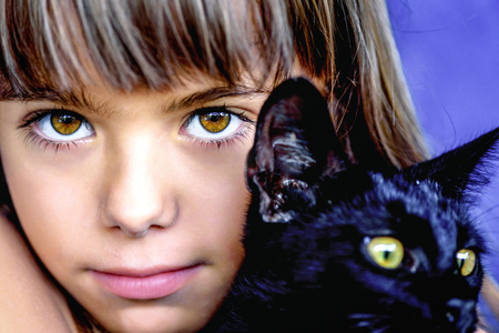 Portrait of a beautiful little girl holding a black catの写真素材