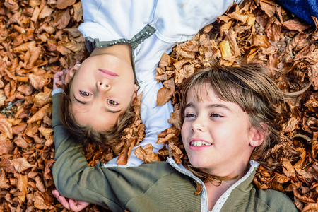 Little girls laying on the bed of leaves in national park Biogradska Gora in autumn, Montenegroの写真素材
