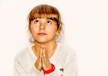 Beautiful little girl praying and looking up, isolated on white