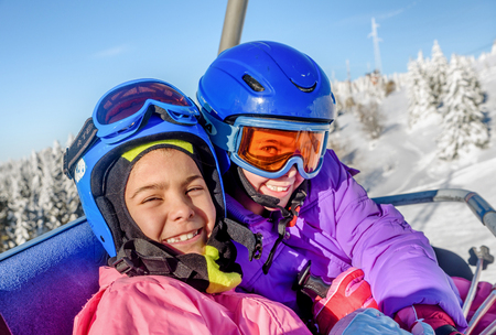 Two little girls riding on ski lift on Kopaonik, Serbiaの写真素材