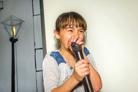 Nine year old girl singing with microphoneの写真素材