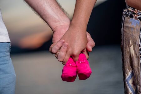 Young couple holding baby shoes