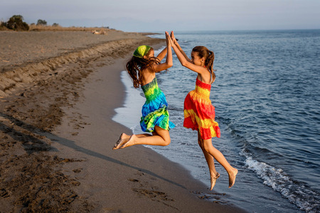 Two happy little girls jumping in the air on the beach