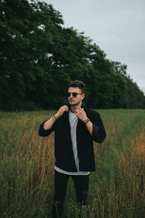 A young handsome guy in dark glasses and a black shirt is comingの写真素材