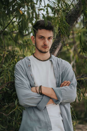 A young handsome surfer guy with a small beard in a light shirt looks at the cameraの写真素材