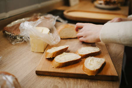Mom cooks breakfast, spreads butter on a baguette. high quality photo