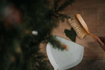 Man sweeps a heart out of Christmas tree needles on the floor. high quality photoの写真素材
