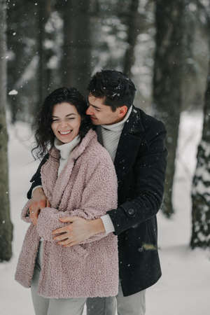 Happy young couple hugging in a snowy forestの写真素材