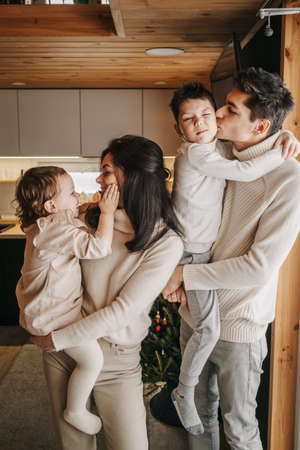 Young happy couple with two children hug and kissの写真素材