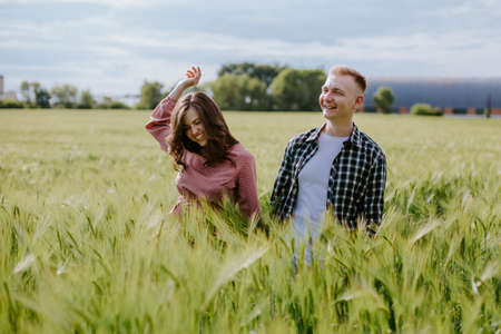 Young couple, a guy and a girl walk around the field and laughの写真素材