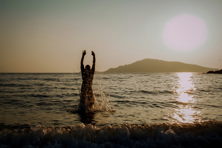 Silhouette of a man jumping out of the seaの写真素材
