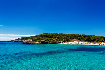 Beautiful beach with turquoise water crowded with tourists in Cala Mondrago, Mallorcaの写真素材