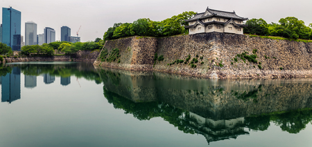 Osaka castle walls and modern office buildings with reflections in moatのeditorial素材