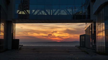 Beautiful sunset view over the sea framed by glass office buildingの写真素材