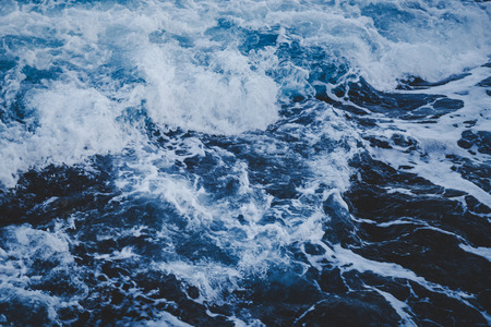 Dramatic foamy sea top view near the rocky shoreline, toned abstract imageの写真素材