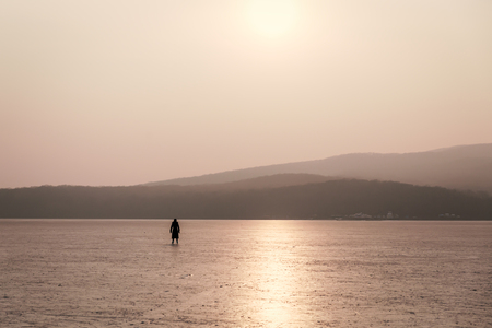 Woman skating on a frozen bay at sunsetの写真素材