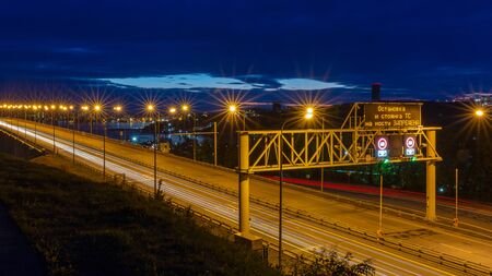 Night view of the bridge with traffic lights and cloudy dramatic sky in Vladivostok, Russia. Sign translation - Stopping and parking the vehicle on the bridge is prohibited.の写真素材