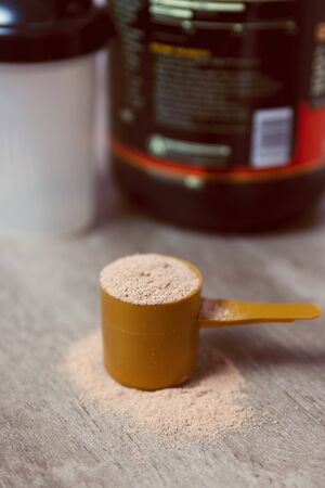 Scoop of chocolate flavour whey protein on a wooden tableの写真素材