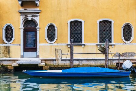 Yellow old facade and motor boat in canal of Chioggia town in Veneto, Italyの写真素材