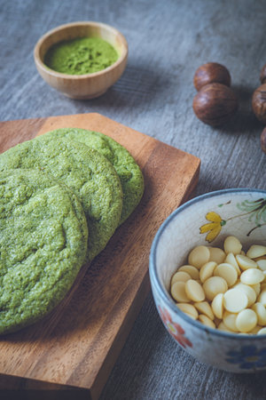 Matcha cookies with macadamia nuts and white chocolate chips on a dark wooden tableの写真素材