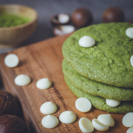 Matcha cookies with macadamia nuts and white chocolate chips on a dark wooden tableの写真素材