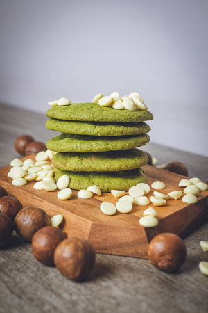 Matcha cookies with macadamia nuts and white chocolate chips on a dark wooden tableの写真素材