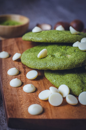 Matcha cookies with macadamia nuts and white chocolate chips on a dark wooden tableの写真素材