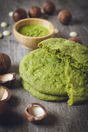 Matcha cookies with macadamia nuts and white chocolate chips on a dark wooden tableの写真素材