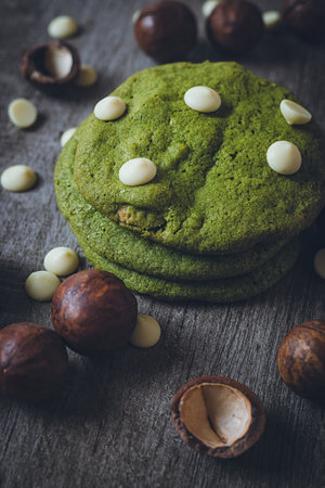 Matcha cookies with macadamia nuts and white chocolate chips on a dark wooden tableの写真素材