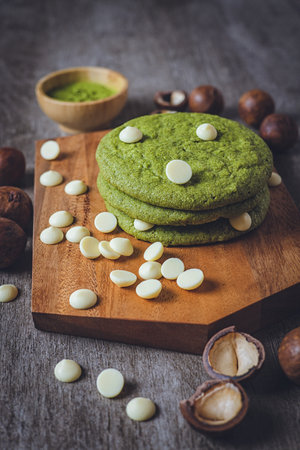 Matcha cookies with macadamia nuts and white chocolate chips on a dark wooden tableの写真素材