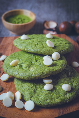 Matcha cookies with macadamia nuts and white chocolate chips on a dark wooden tableの写真素材