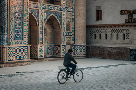 Man riding a bicycle near old madrasah in Bukhara, Uzbekistanの写真素材