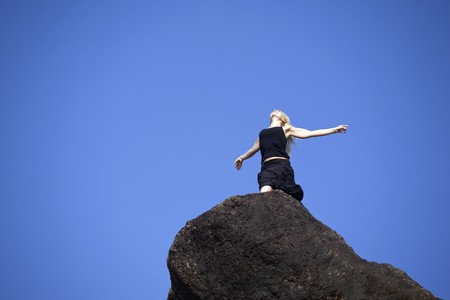 Attractive girl on rock against the blue sky.の写真素材