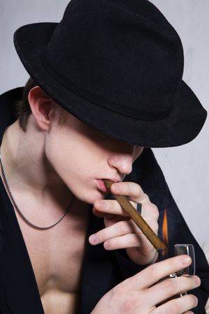 portrait of a guy smoking a cigar on gray backgroundの写真素材