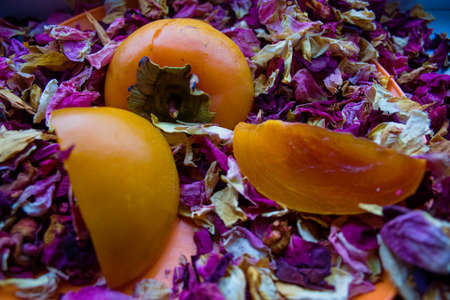 persimmon amid the dried leaves of the roseの写真素材