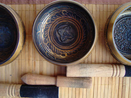 three Tibetan bowls with sticks on the background of straw Matの写真素材