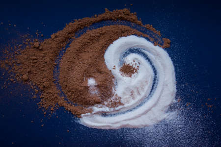 he Yin and Yang of milk powder and cocoa powder on a blue backgroundの写真素材