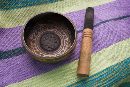 Tibetan singing bowl with stick on the background of linen Mat