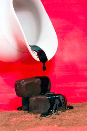 candy poured chocolate from a white pitcher on a red backgroundの写真素材