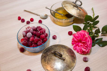 frozen cherry in a glass vase, honey and pink roses on wooden backgroundの写真素材