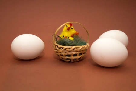 eggs and decorative basket of chickens on a brown background. wicker basketの写真素材