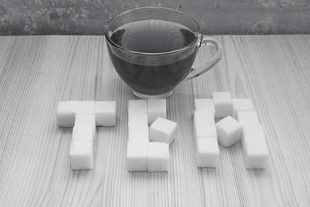 glass mug with tea and the word tea is made of sugar cubes in black and white colorsの写真素材