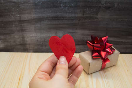 box with a gift on a black background and a hand with paper heart,the concept of Valentine's day, anniversary, romantic giftの写真素材