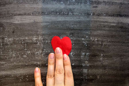 hand holding heart from the red paper on black background.the concept of life, health, heart disease.の写真素材