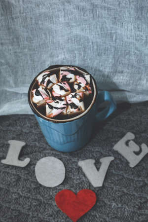 cocoa in blue mug, the letters LOVE and a little red cardboard heart on gray knitted backgroundの写真素材