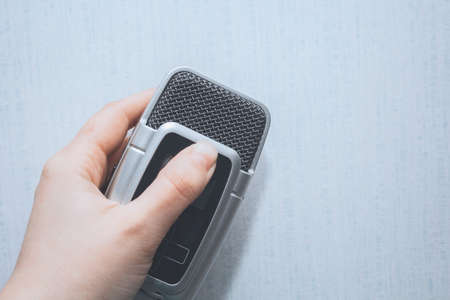 Hand holding microphone/voice recorder on a white background in retro colors